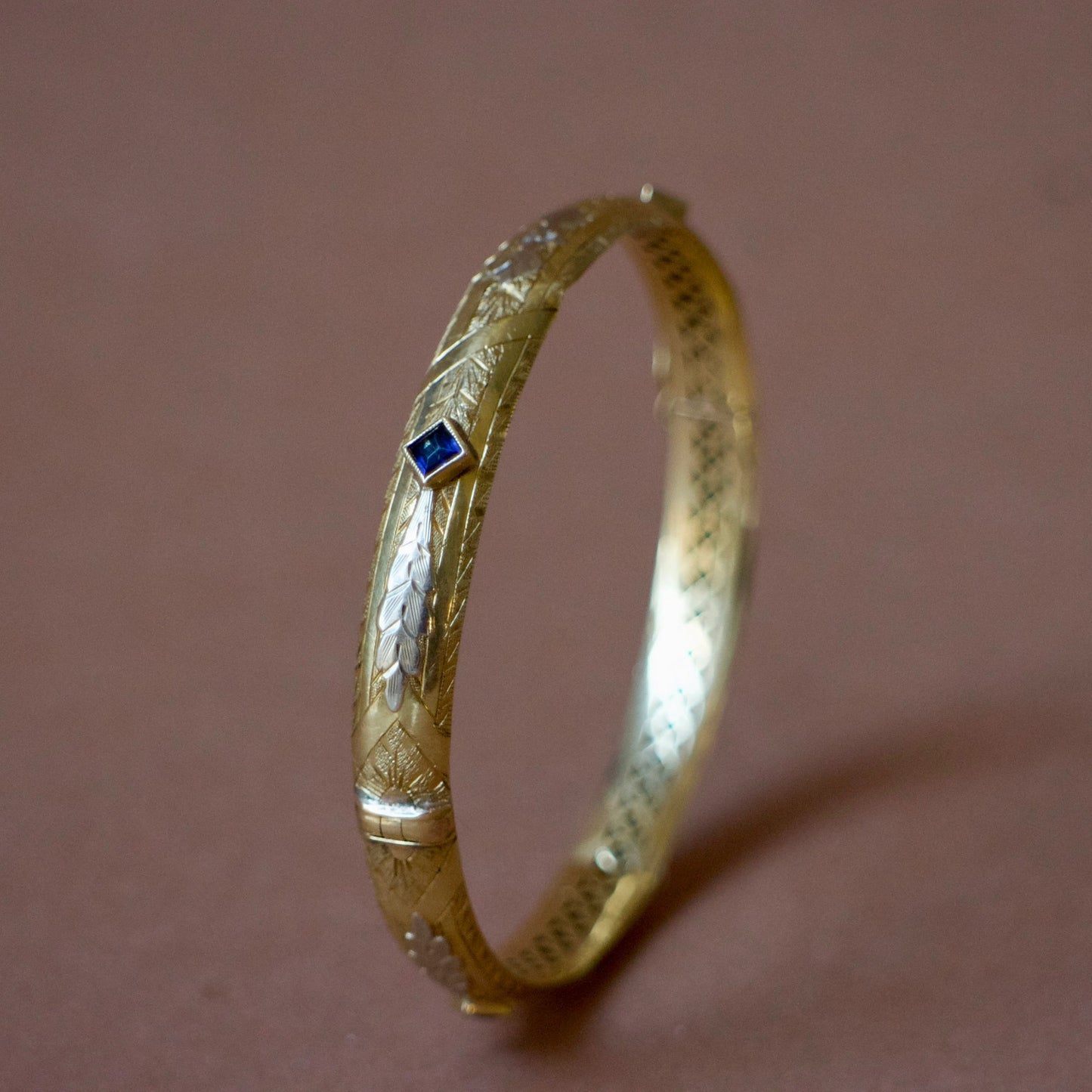 Bracelet ancien jonc rigide ouvrant en or jaune 18K, motifs floraux ciselés en or gris 18k et saphirs bleus