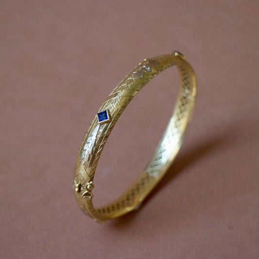 Bracelet ancien jonc rigide ouvrant en or jaune 18K, motifs floraux ciselés en or gris 18k et saphirs bleus