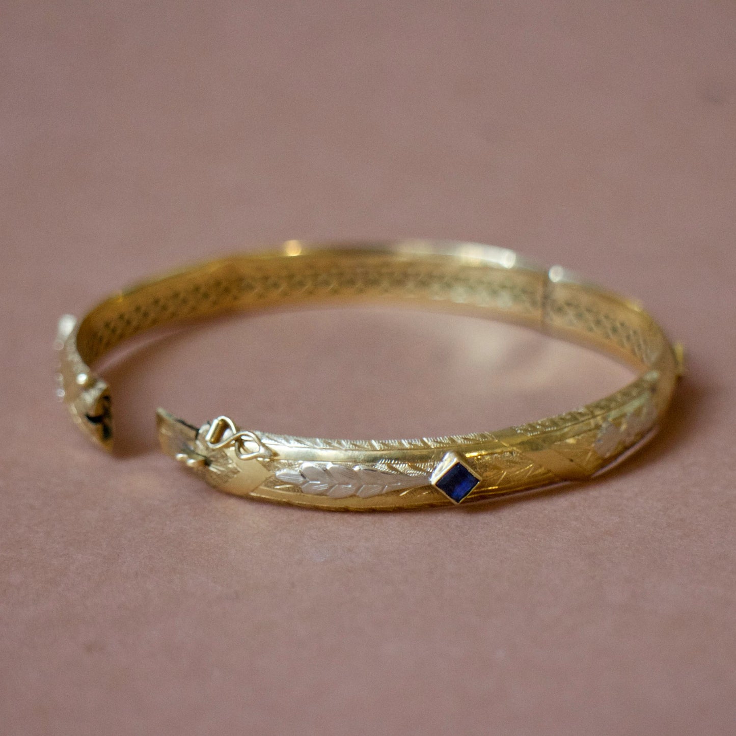 Bracelet ancien jonc rigide ouvrant en or jaune 18K, motifs floraux ciselés en or gris 18k et saphirs bleus