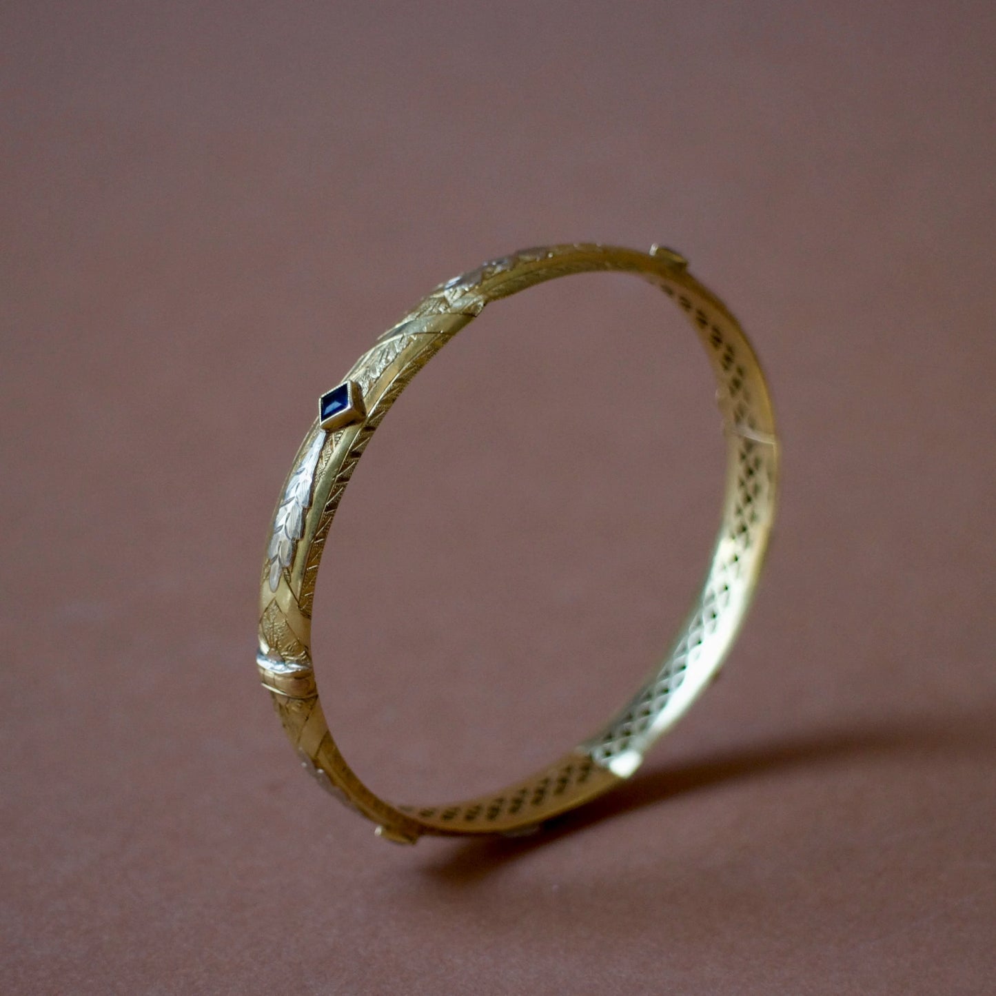 Bracelet ancien jonc rigide ouvrant en or jaune 18K, motifs floraux ciselés en or gris 18k et saphirs bleus