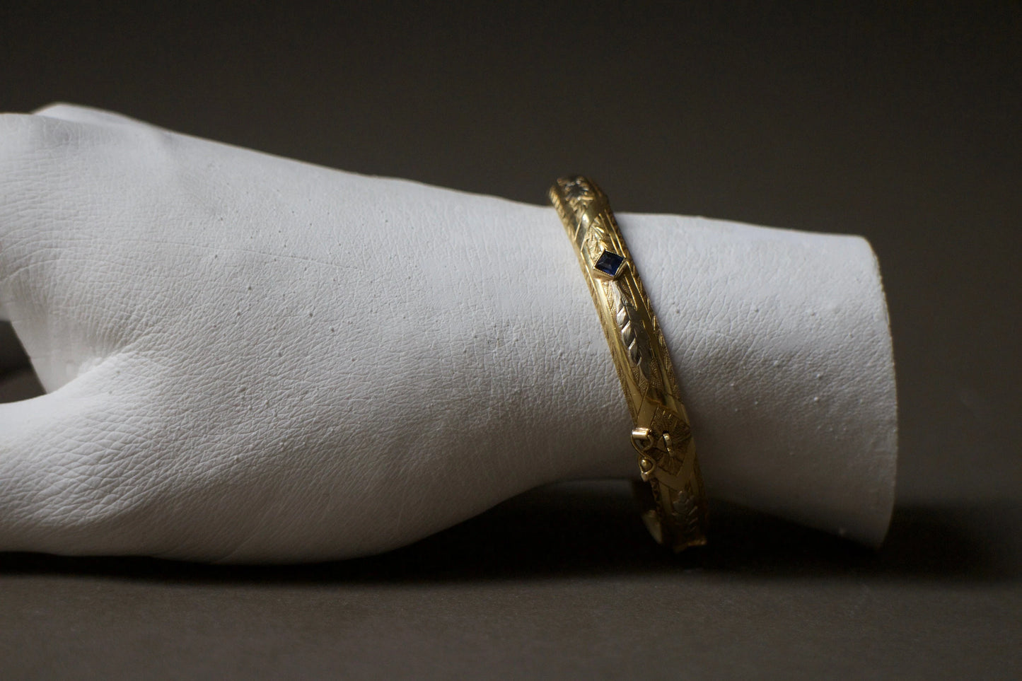 Bracelet ancien jonc rigide ouvrant en or jaune 18K, motifs floraux ciselés en or gris 18k et saphirs bleus
