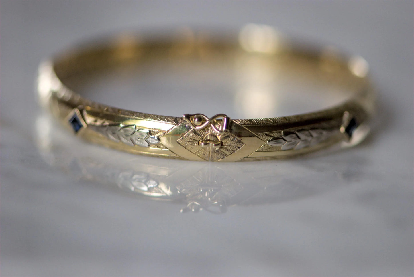 Bracelet ancien jonc rigide ouvrant en or jaune 18K, motifs floraux ciselés en or gris 18k et saphirs bleus
