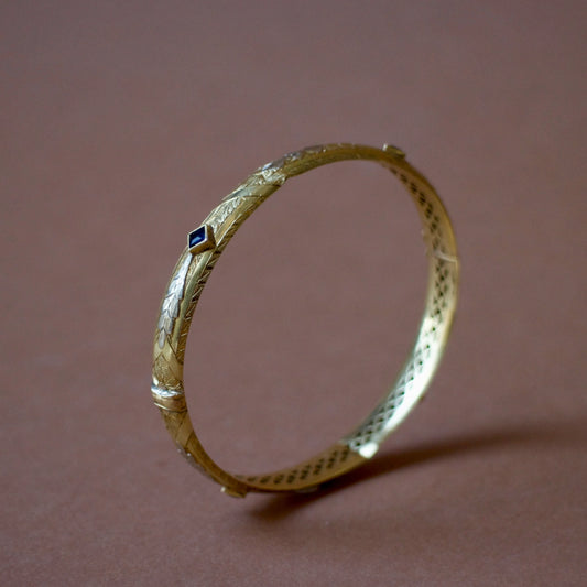 Bracelet ancien jonc rigide ouvrant en or jaune 18K, motifs floraux ciselés en or gris 18k et saphirs bleus